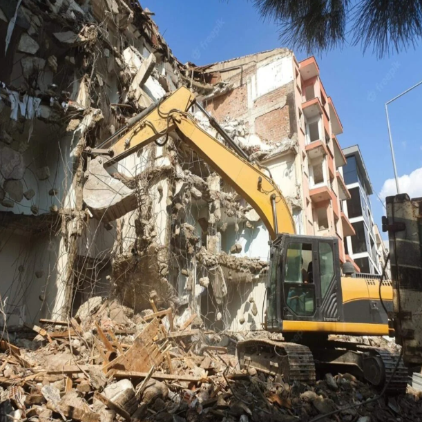 أفضل مقاول هدم في السعودية - مقاول محترف يرتدي خوذة ويحمل مخطط أمام مبنى مهدوم